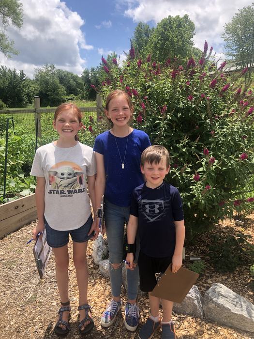 3 kids standing in front of a plant
