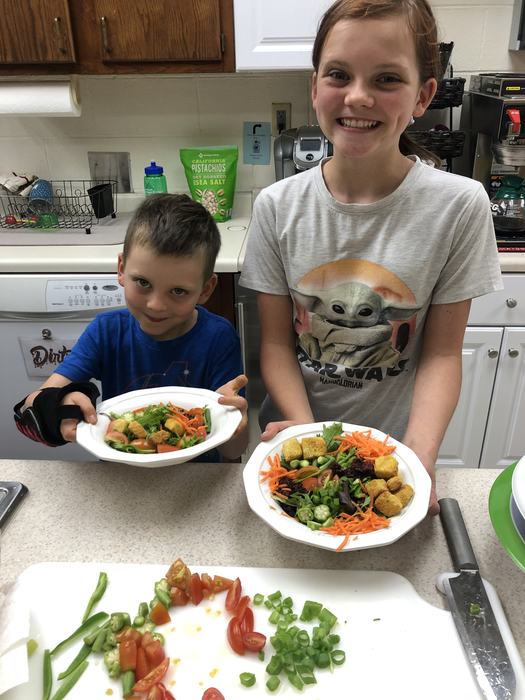 Two kids with salad bowls