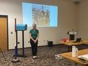Woman standing in front of a projected photo of a child on a horse during a presentation