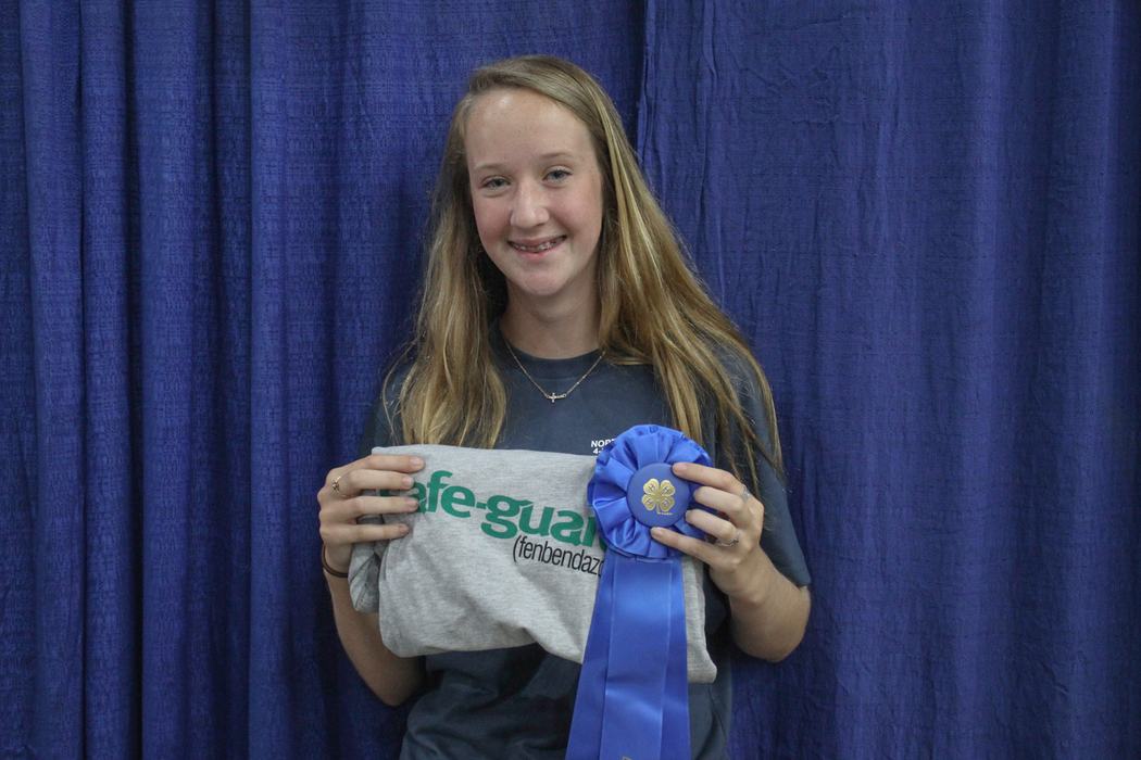 Teen girl holding folded gray shirt reading "afe-guard" and a blue ribbon