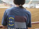 Person from behind wearing NC 4‑H Horse Program T-shirt in indoor horse arena
