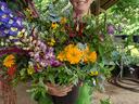Person wearing glasses holding a large mixed flower arrangement in a black pot