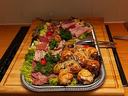 Platter of assorted cold cuts, savory rolls and parsley garnish on a wooden serving board