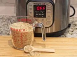 Pyrex measuring cup filled with oats, wooden scoop with oats, Instant Pot display reading "OFF"