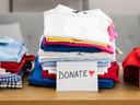 Three piles of folded clothes on a table labeled KEEP, DONATE ♥, and DISCARD