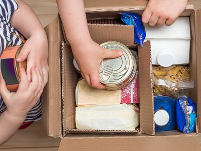 Hands adding food to donation box.