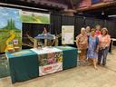 Six women standing beside an NC State Extension Master Gardener booth at an indoor fair