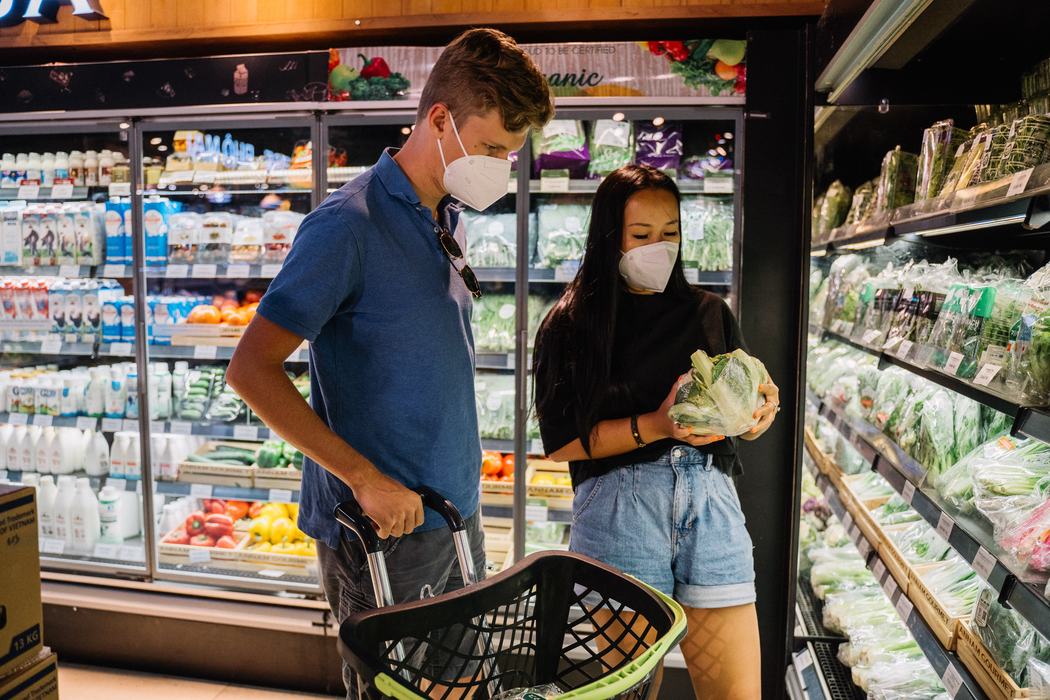 Two shoppers observe lettuce in grocery store