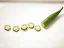 A piece of partially sliced okra on a white plate