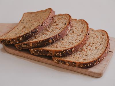 Four slices of multigrain bread stacked on a wooden cutting board