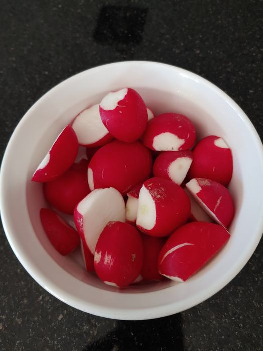 cut raw radishes in a white bowl