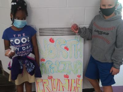 two students holding apples with "North Carolina Crunch" Sign