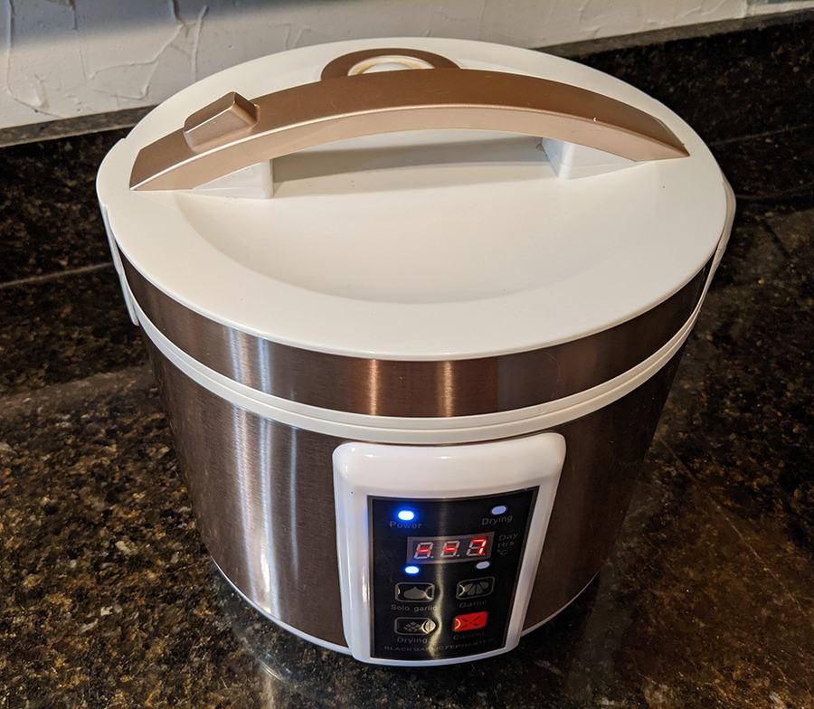 Stainless electric food dehydrator with white lid and handle, lit digital control panel