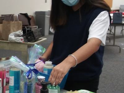 Person wearing surgical mask arranging toiletries and toothbrushes on a table