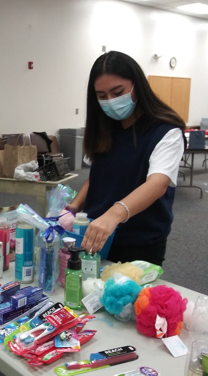 Person wearing surgical mask arranging toiletries and toothbrushes on a table