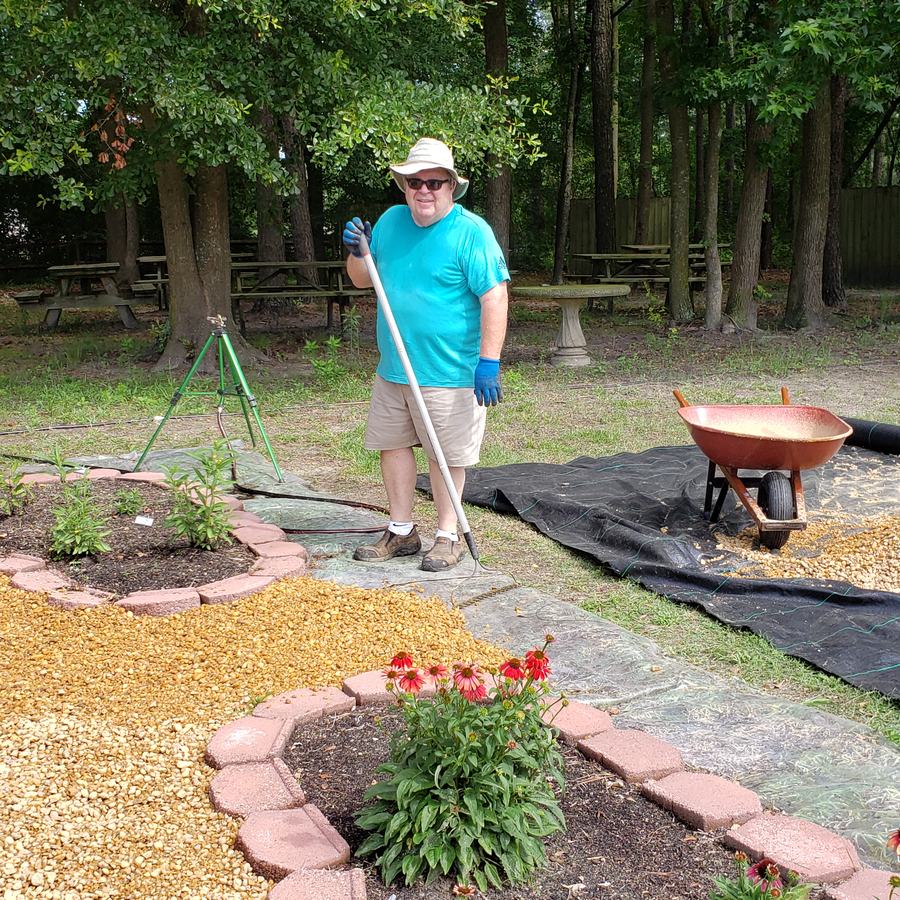 man holding rake working in a garden