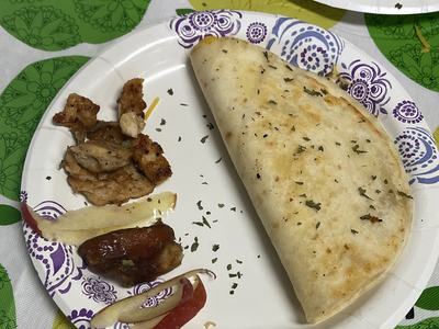 Folded quesadilla on paper plate with grilled chicken pieces and apple slices