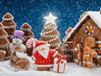 Gingerbread village: Santa cookie with gift beside gingerbread house and trees in falling snow