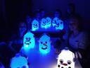 Children seated around a table displaying glowing milk-jug snowman lanterns