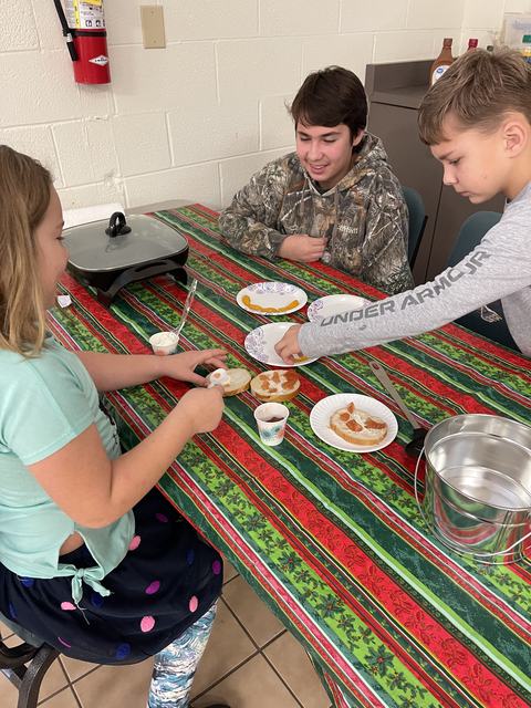 Three kids assembling bagels with cream cheese at a table; sleeve reads UNDER ARMOUR