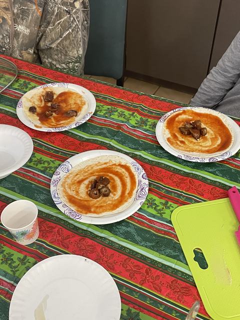 Three paper plates with tortillas swirled with red sauce and small meat pieces