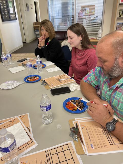 Three adults tasting food at a table with score sheets labeled "Judging Instructions."