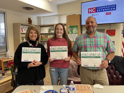 Three people holding certificates labeled "Certificate of Appreciation" beneath NC Cooperative Extension logo