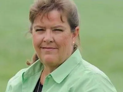 Woman in green collared shirt facing camera outdoors