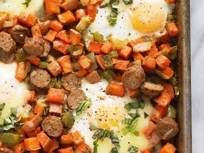 Sheet-pan breakfast hash with baked eggs, sausage slices, sweet potatoes, peppers, basil