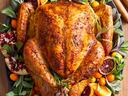 Roasted whole turkey on platter garnished with herbs, citrus slices, kumquats and pomegranate