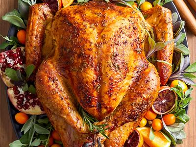 Roasted whole turkey on platter garnished with herbs, citrus slices, kumquats and pomegranate