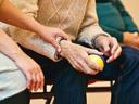 Caregiver holding elderly person's forearm while they hold a yellow stress ball.