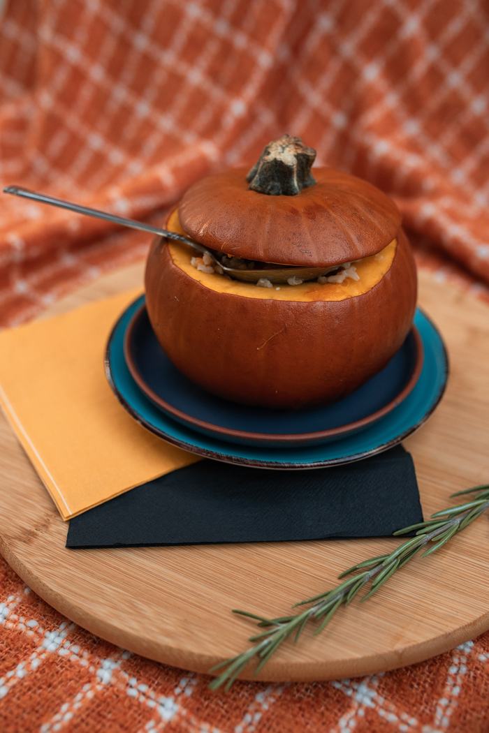 pumpkin with top cut off and spoon inside on a small plate