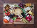 Charcuterie board with cheeses, crackers, grapes, meats, nuts, pickles, and vegetables