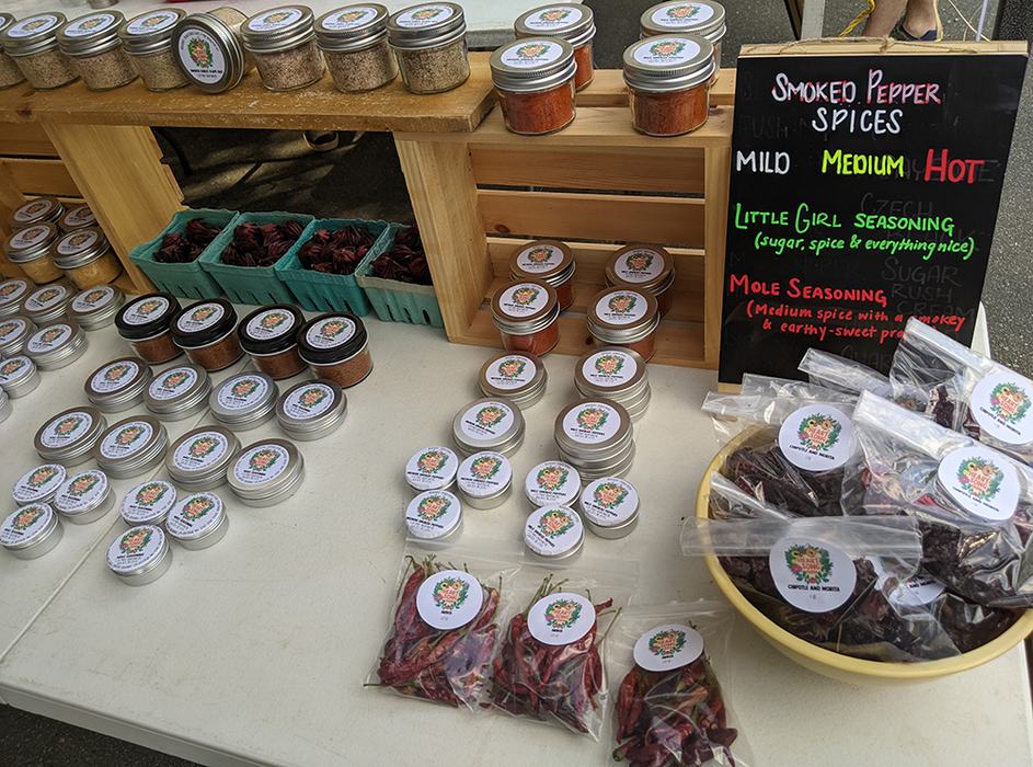 Jars and bags of dried peppers with sign reading "Smoked Pepper Spices: Mild Medium Hot"