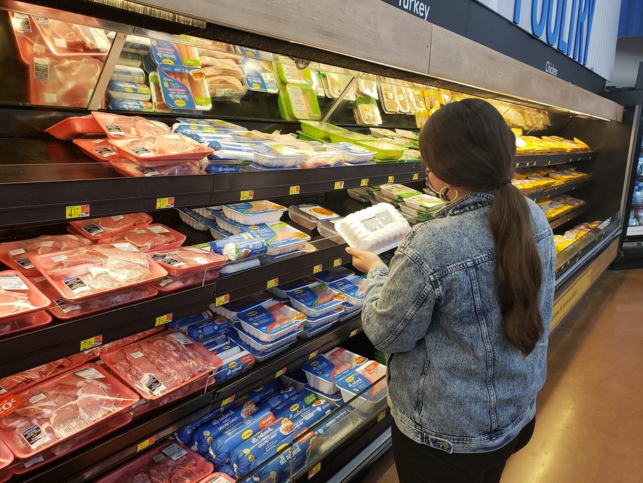 lady viewing meat packaging in grocery store