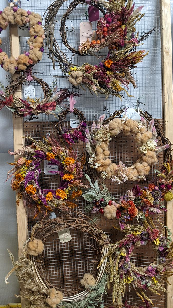 Assorted dried floral wreaths hanging on a wire display grid