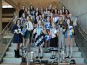 Group of young women and adults on staircase holding ribbons, plaques, and trophies