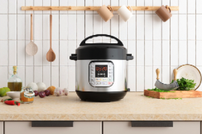 Electric pressure cooker on kitchen countertop with cutting board, utensils, and ingredients