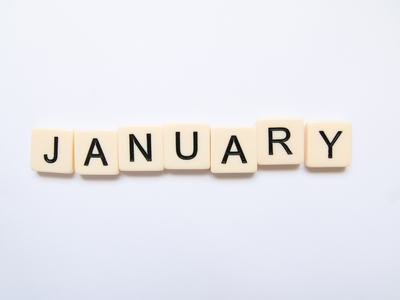 Scrabble-style letter tiles arranged to spell JANUARY on a white background