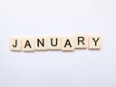 Scrabble-style letter tiles arranged to spell JANUARY on a white background