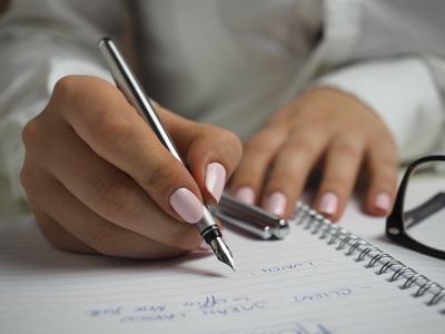 hand holding pen writing in a notebook