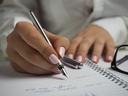 hand holding pen writing in a notebook