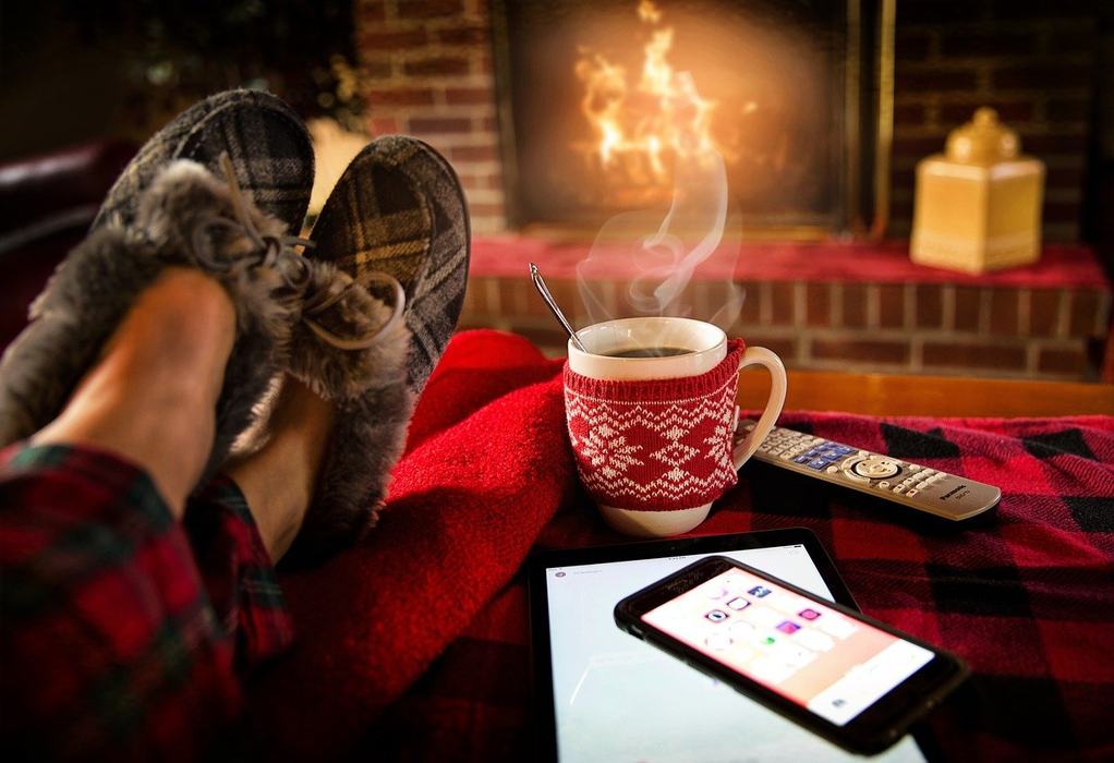 feet with slippers on, propped on ottoman with coffee or tea