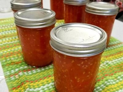 Sealed mason jars filled with orange jam on a green-striped dish towel