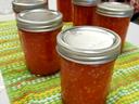 Sealed mason jars filled with orange jam on a green-striped dish towel