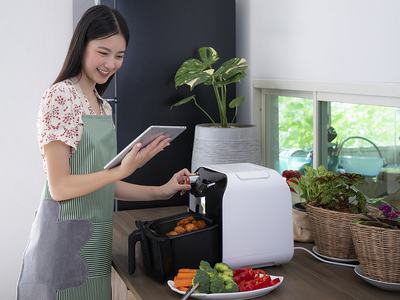Asian female is cooking with her Air Fryer making a fried chicken for dinner by using very little oil. 