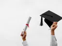 Hands holding a rolled diploma and a mortarboard graduation cap against a white sky