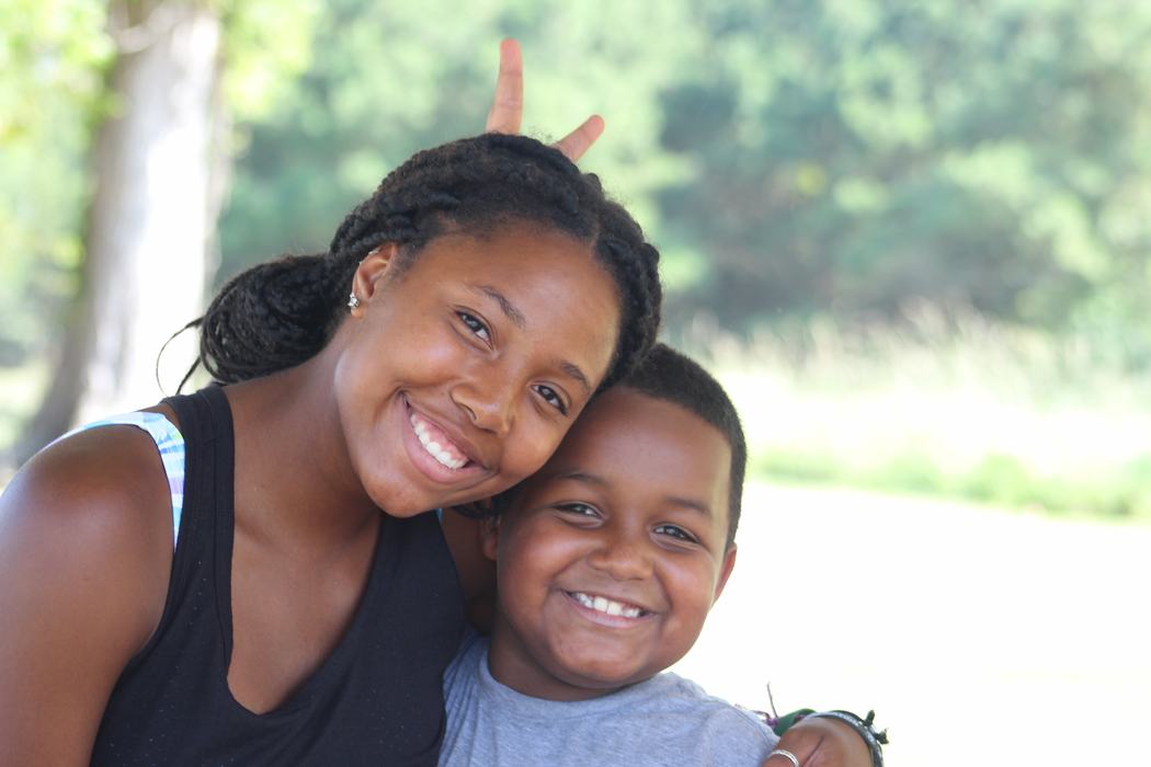 Young woman and boy smiling, woman making bunny ears behind boy