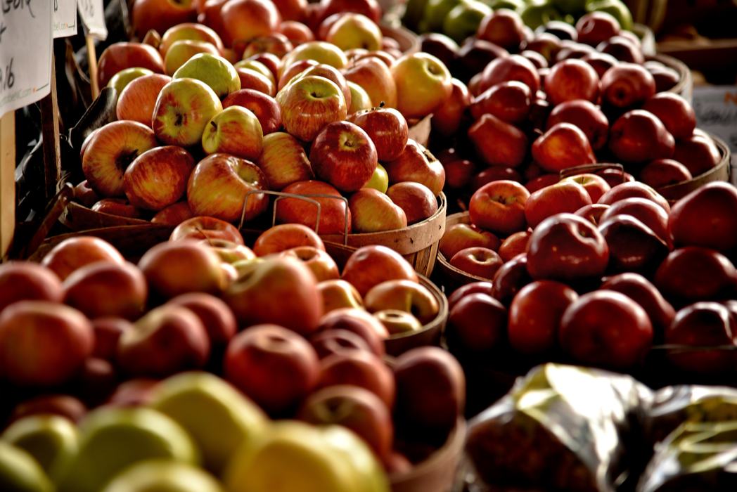 Baskets of red and green apples arranged on a market stall